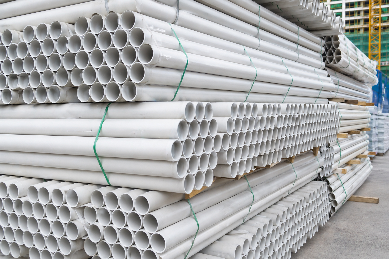 Stack of heavy-duty extruded PVC pipes and structural profiles used for construction infrastructure and fluid transport.