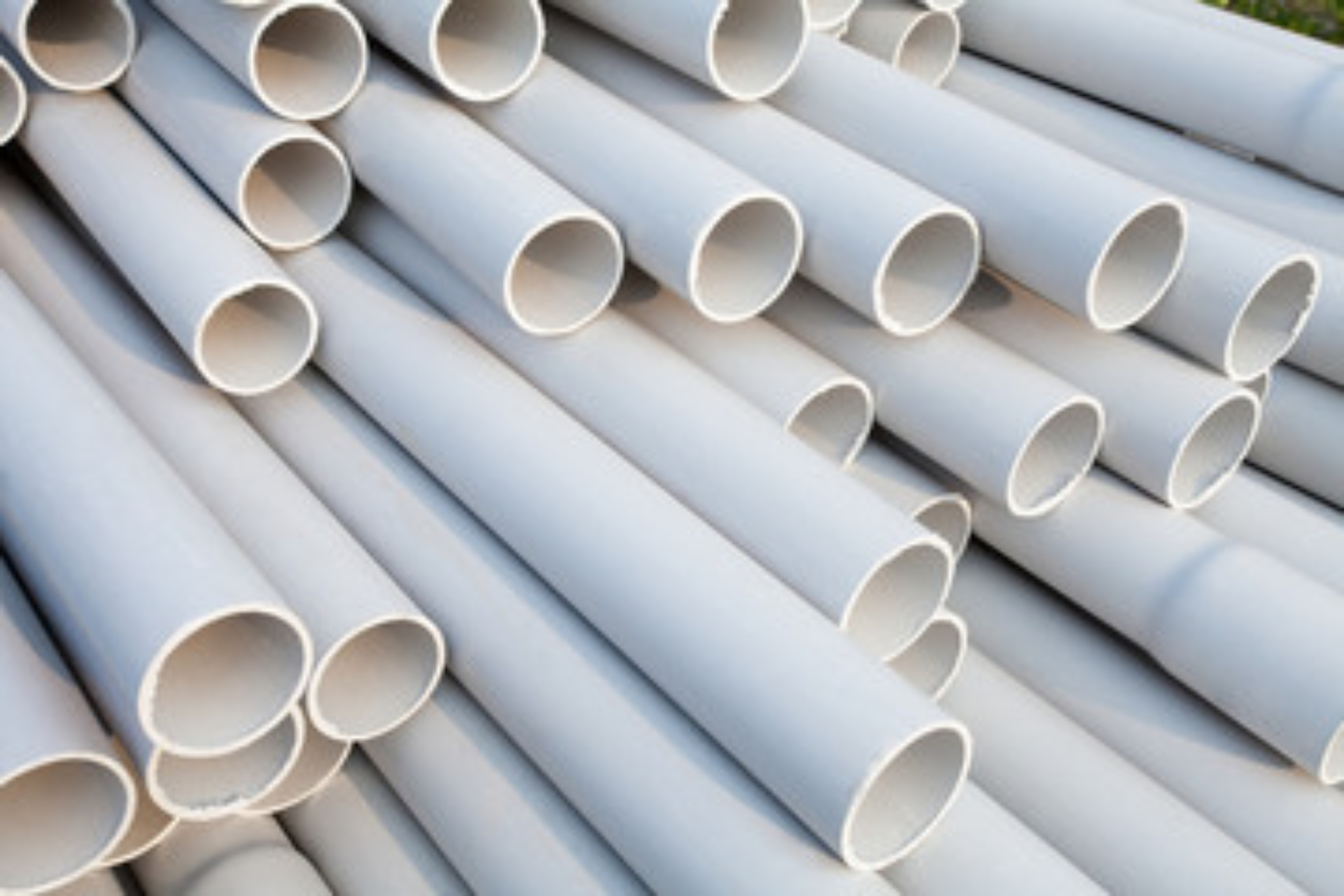 A neat stack of finished rigid PVC pipes in a manufacturing facility, demonstrating the dimensional stability and surface quality achieved after the extrusion process.